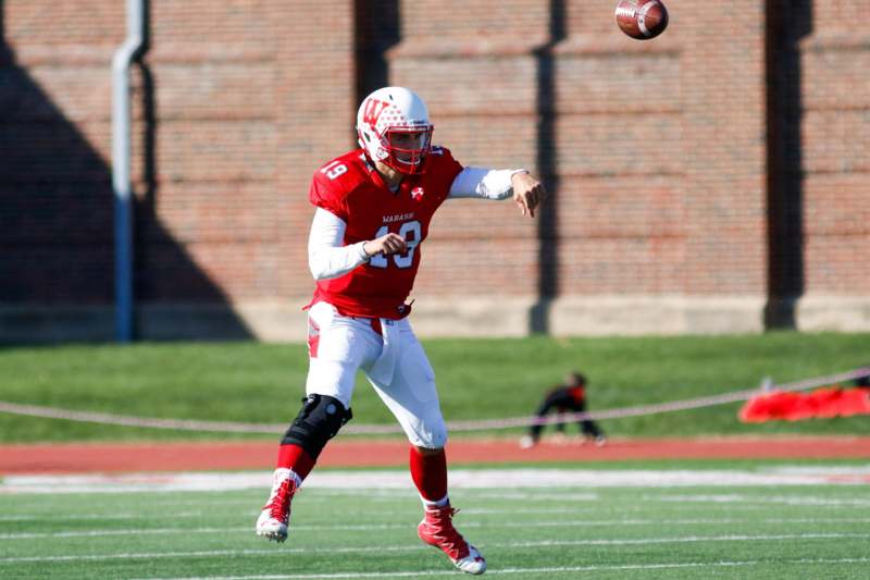 a football player in a red uniform throwing a football
