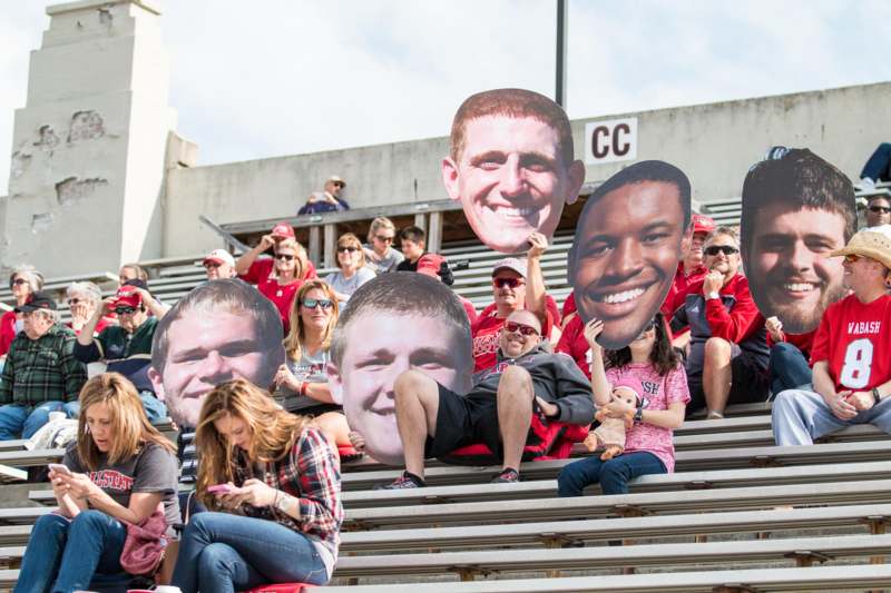 a group of people sitting on bleachers with large cutouts of people
