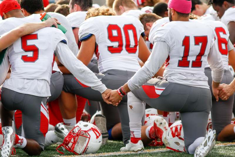 a group of football players holding hands