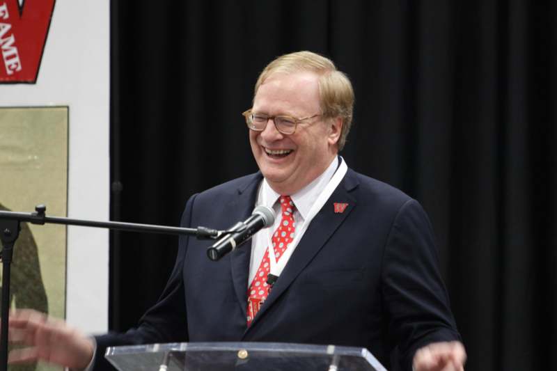 a man in a suit and tie laughing at a podium