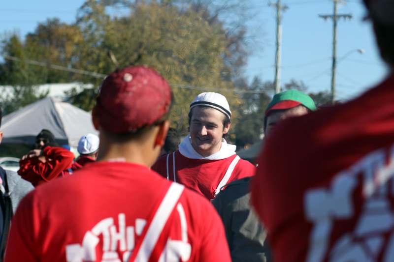 a man in red shirt and white hat with a mustache standing in a crowd
