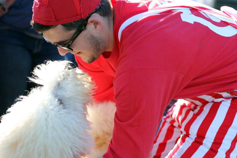 a man in red shirt and sunglasses petting a dog