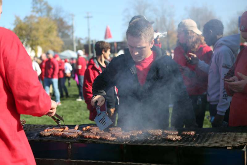 a man grilling meat on a grill with people in the background