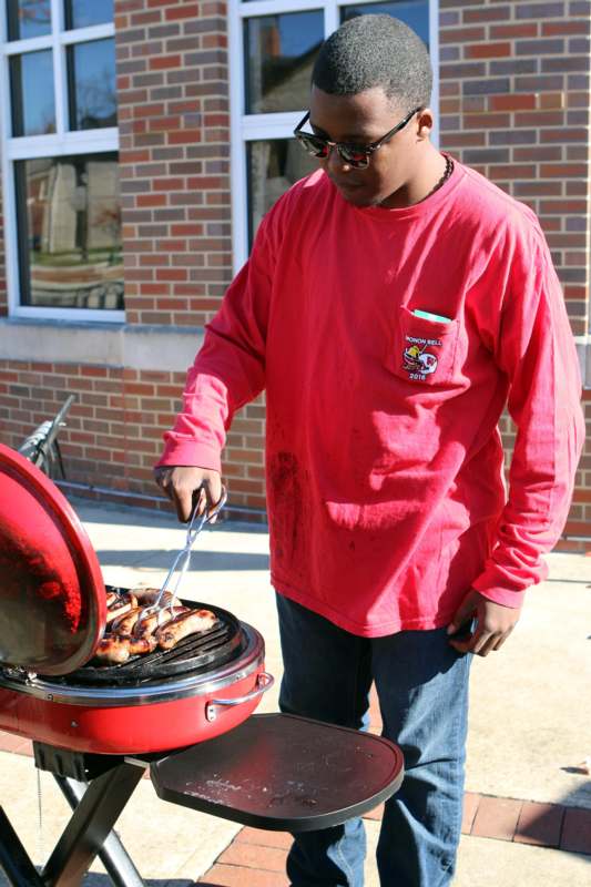 a man in a red shirt grilling sausages