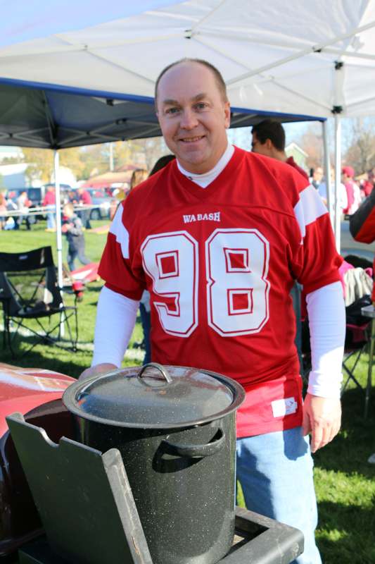 a man in a red jersey standing next to a large black pot