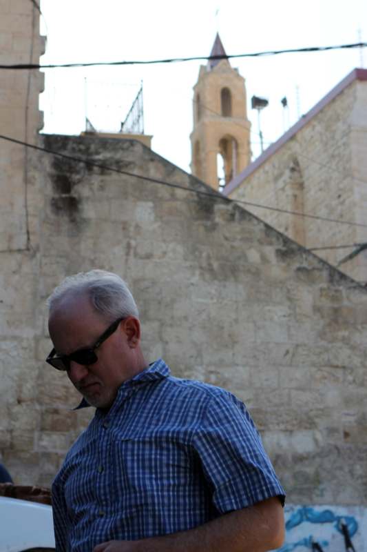 a man in sunglasses standing in front of a stone wall