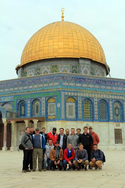 a group of people posing for a photo in front of Dome of the Rock