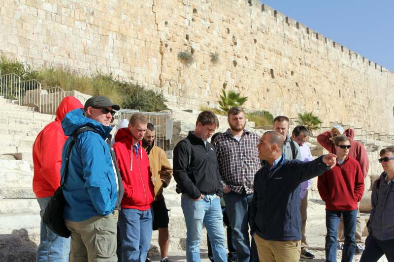 a group of people standing in front of a stone wall