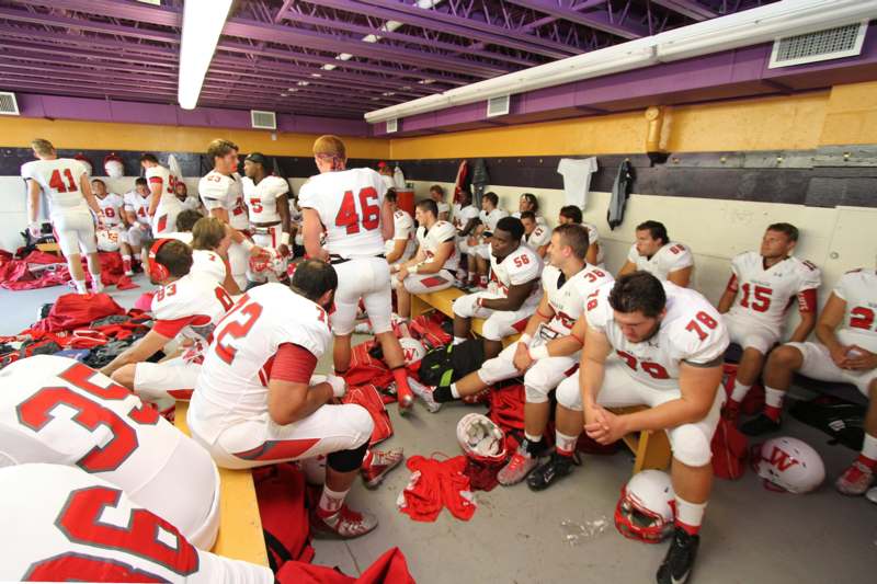 a group of football players sitting in a locker room