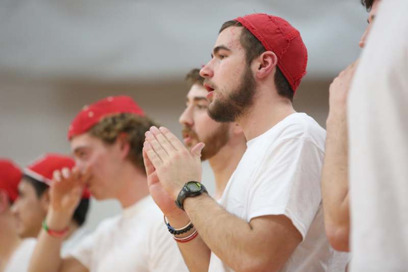 a group of men in white shirts with red hats