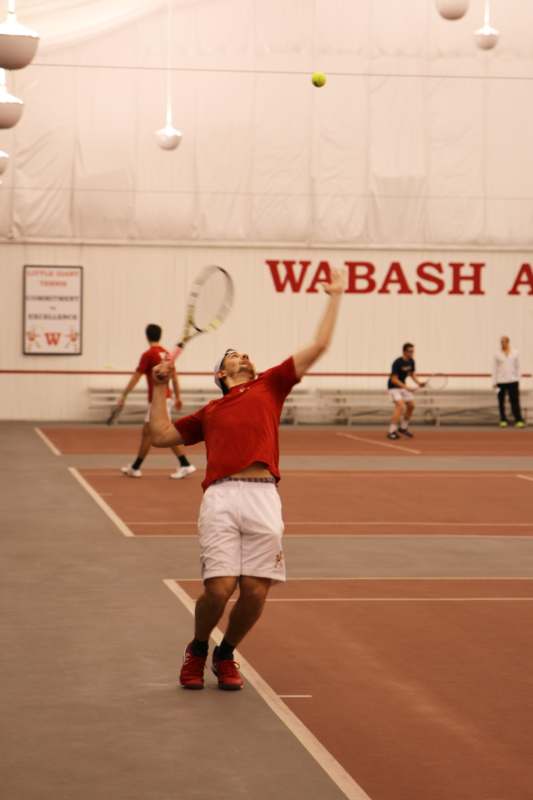 a man in a red shirt and white shorts playing tennis
