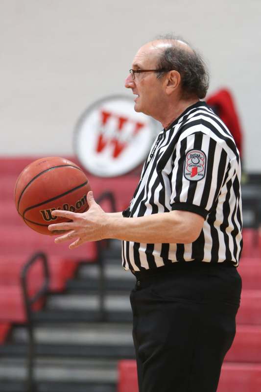 a man in a referee shirt holding a basketball