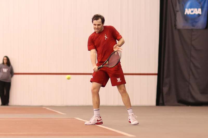 a man in red shirt holding a tennis racket and a ball