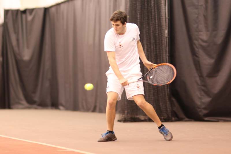 a man holding a tennis racket and a ball
