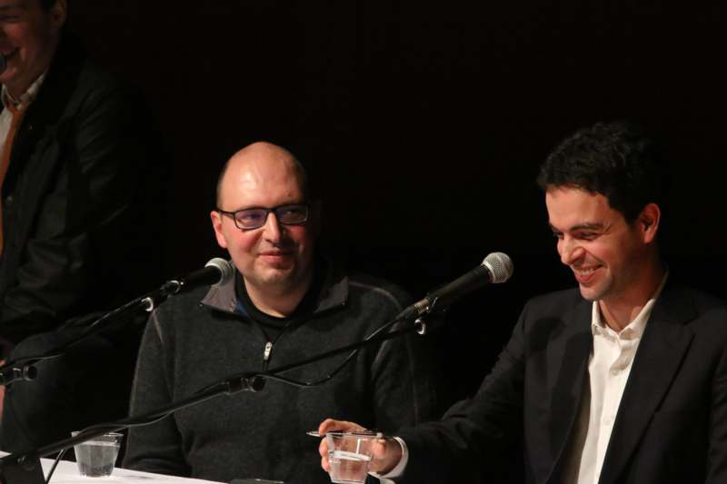 two men sitting at a table with microphones