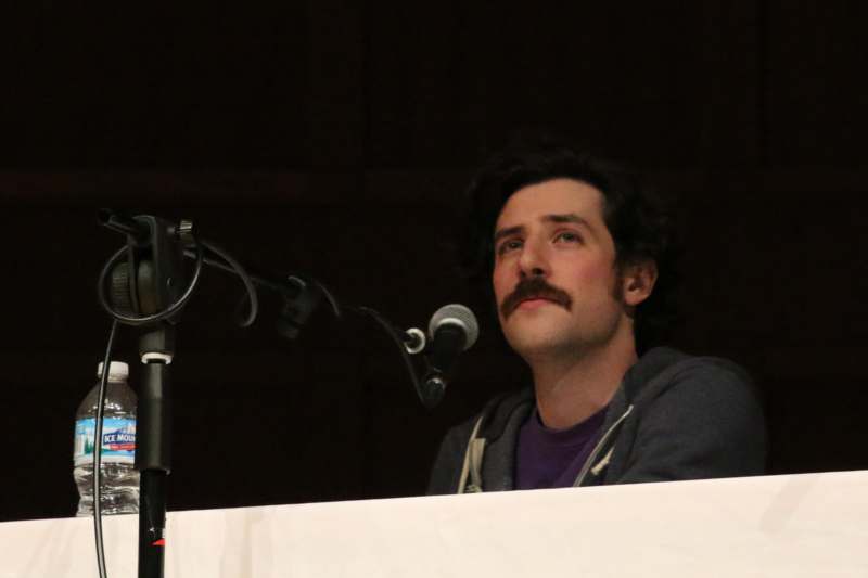 a man with a mustache behind a microphone