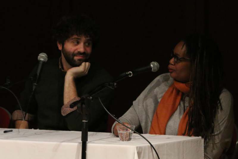 a man and woman sitting at a table with microphones