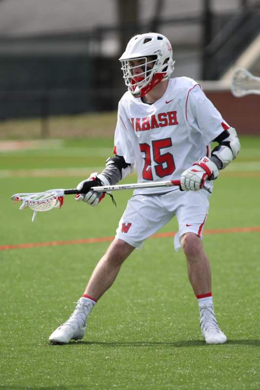 a man wearing a white and red uniform holding a lacrosse stick
