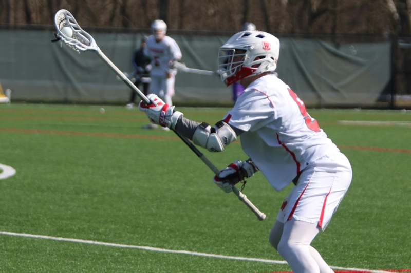 a person in a white uniform holding a lacrosse stick
