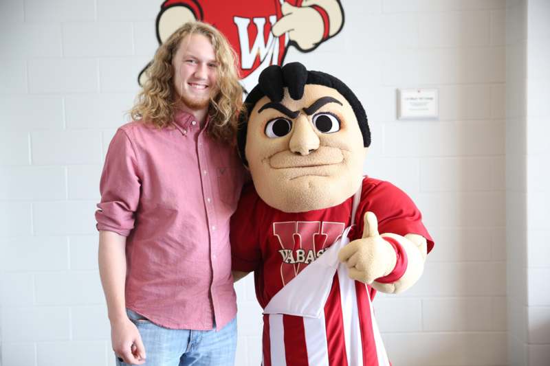 a man standing next to a mascot