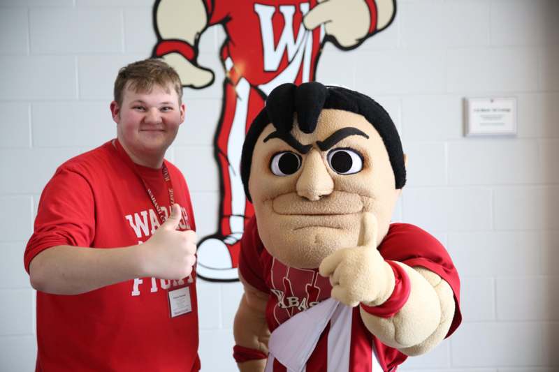 a man in a red shirt with a mascot