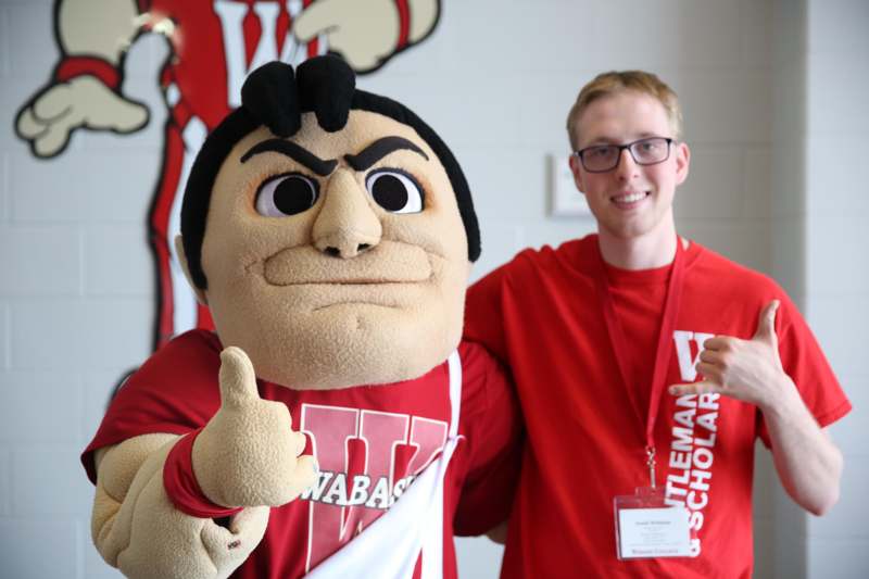 a man in glasses giving a thumbs up with a mascot