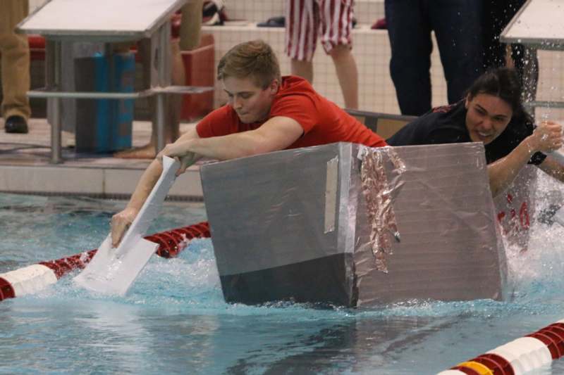 a man in a red shirt holding a box in a pool