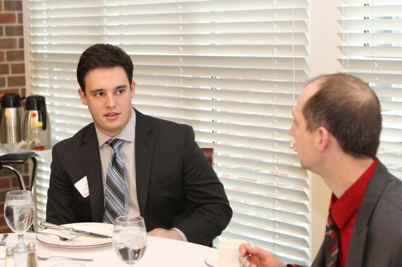a man in suit and tie sitting at a table with a man in a tie