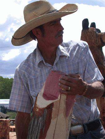 a man in a cowboy hat holding a piece of wood