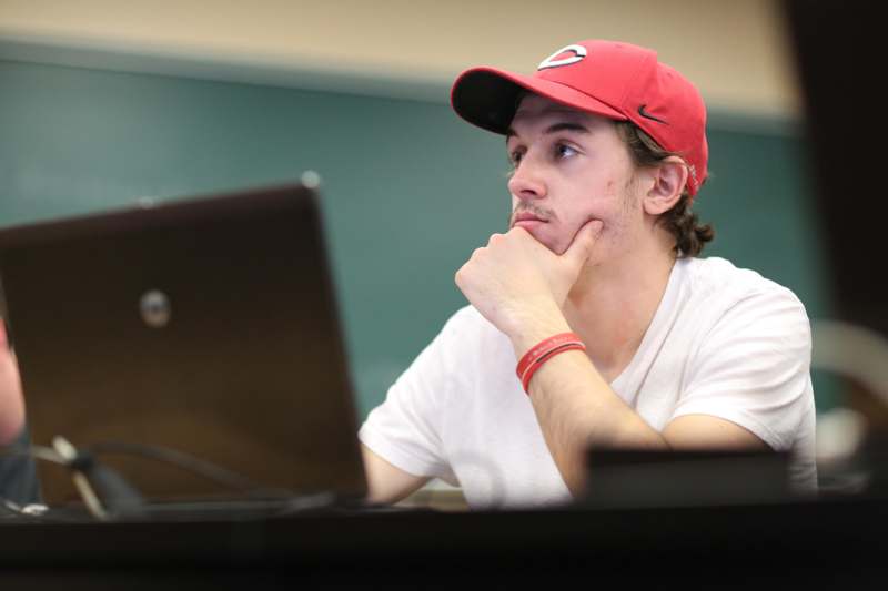 a man in a red hat looking at a laptop