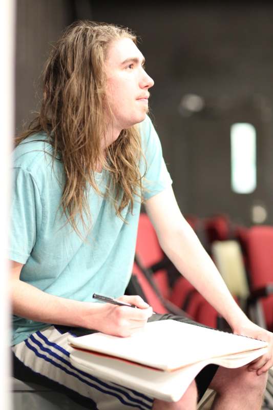 a man with long hair holding a pen and paper