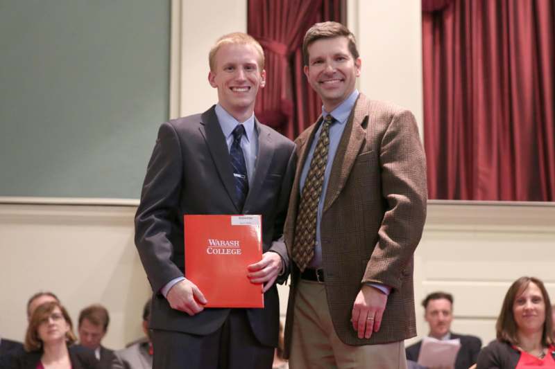 two men in suits holding a red book