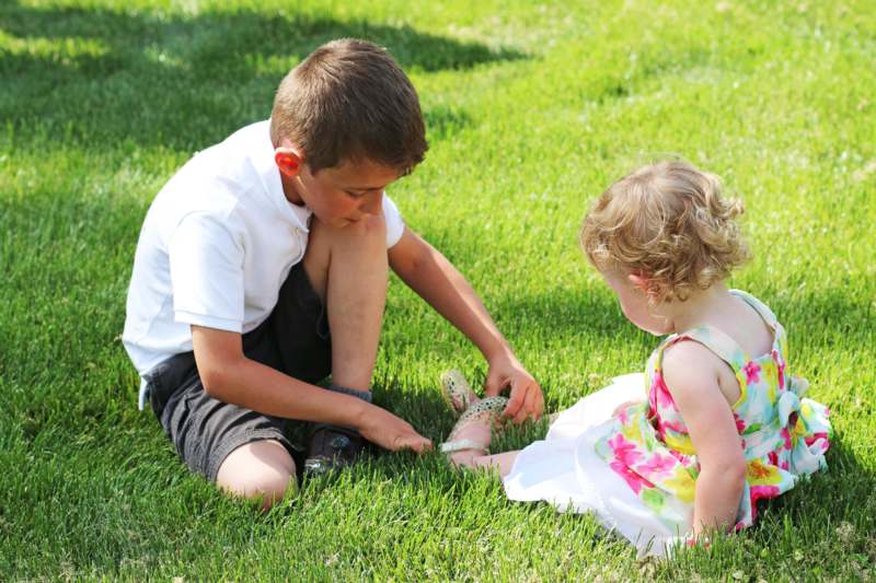 a boy and girl sitting on grass