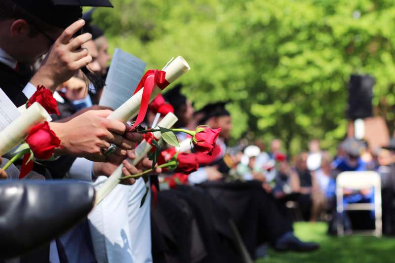 a group of people holding diplomas and roses