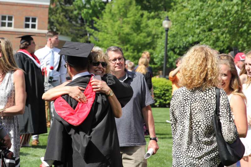 a man in a cap and gown hugging a woman in a graduation cap