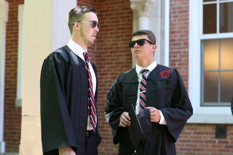 two men wearing black robes and sunglasses