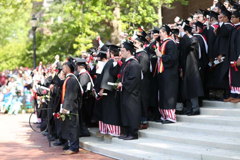 a group of people in black gowns and caps standing on stairs
