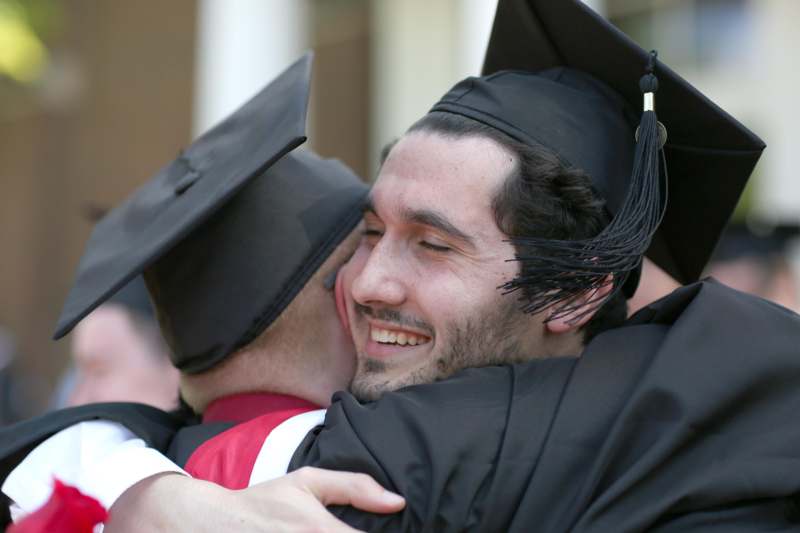 a man in cap and gown hugging another man