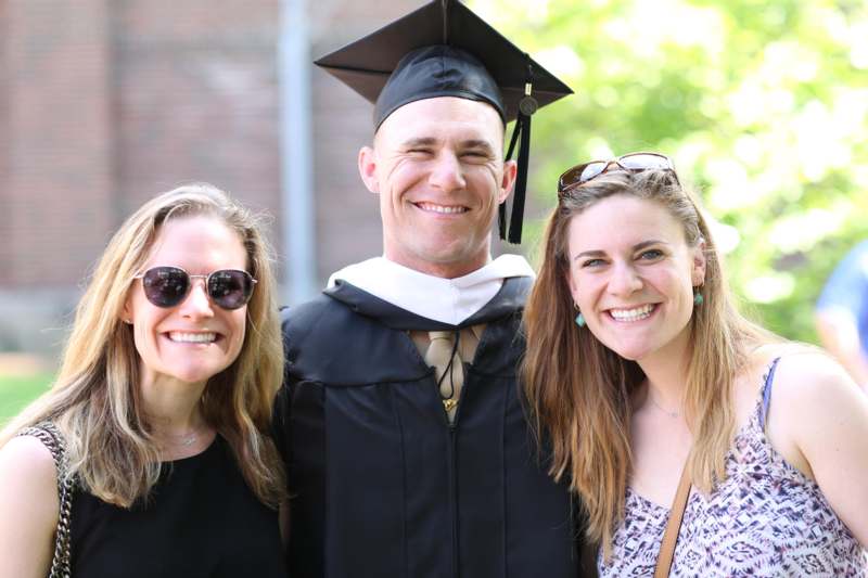 a man in a graduation cap and gown with two women