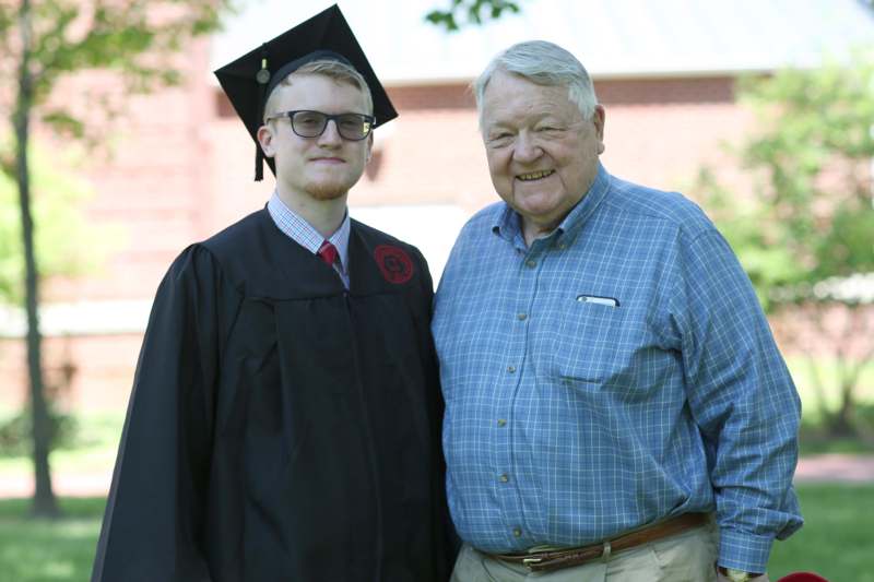 a man in a graduation cap and gown standing next to a man