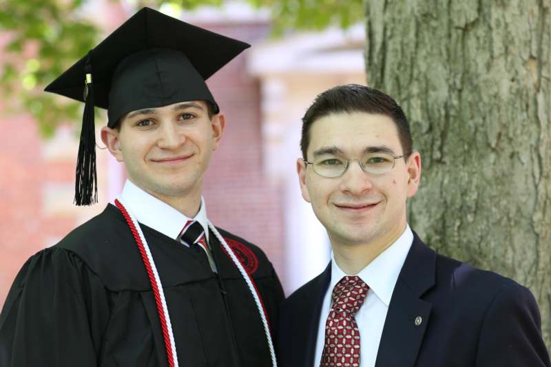 a man in a graduation cap and gown standing next to another man