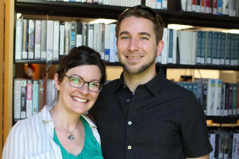 a man and woman smiling in front of a bookshelf