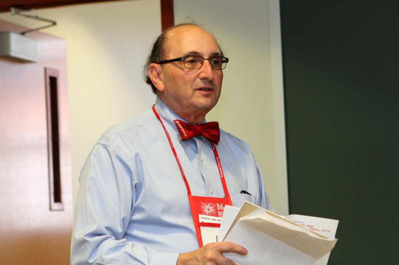 a man wearing a bow tie and a red lanyard holding papers