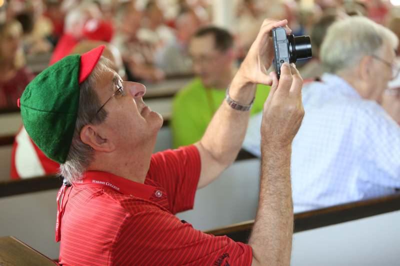 a man in a green hat taking a picture of a crowd