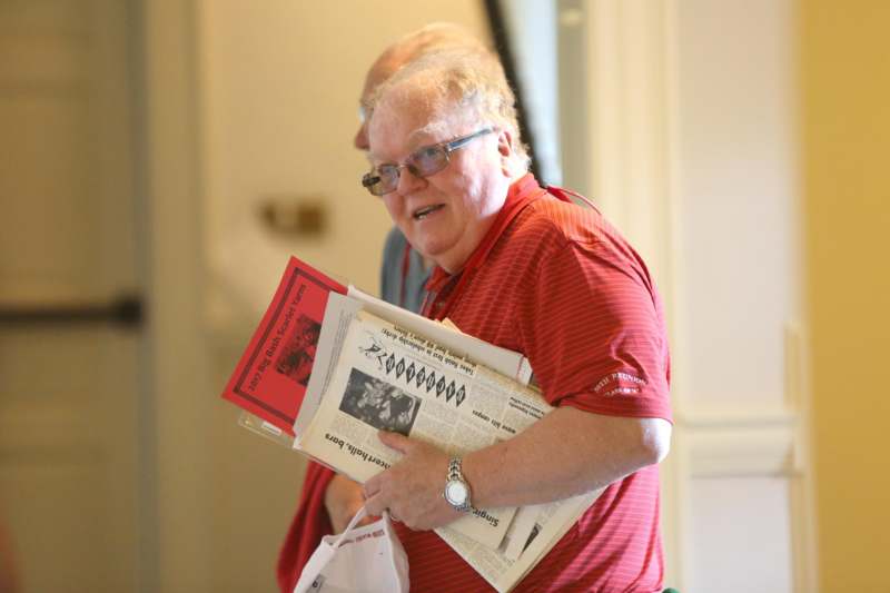 a man in a red shirt holding a stack of newspapers