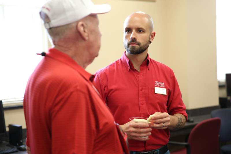 a man in red shirt talking to a man in a white hat