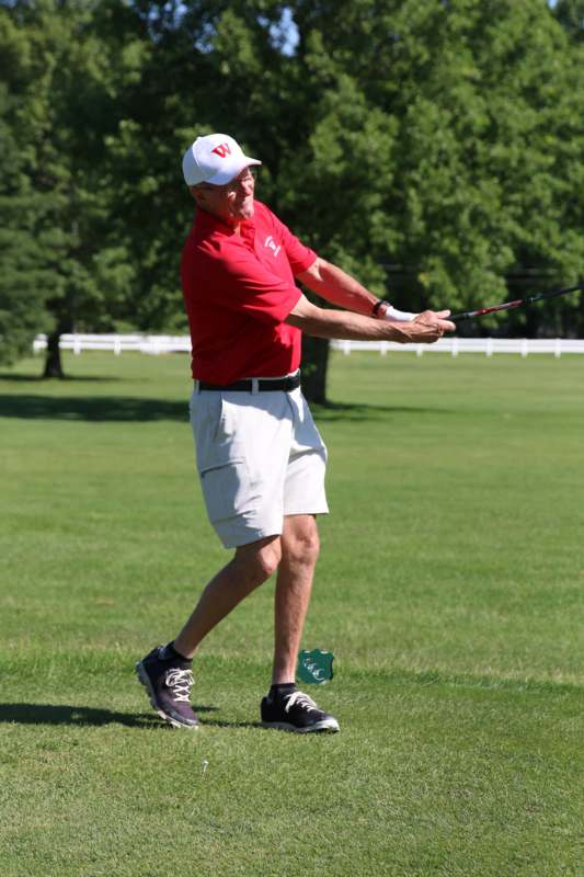 a man in a red shirt and white hat holding a golf club
