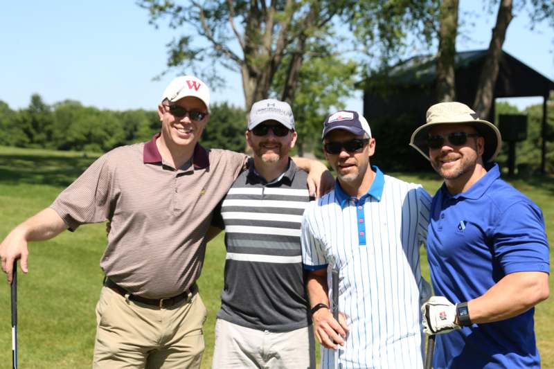 a group of men standing together on a golf course
