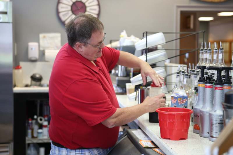 a man in a red shirt pouring a drink into a red bucket