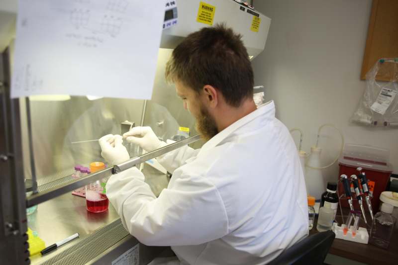 a man in a white coat working in a laboratory